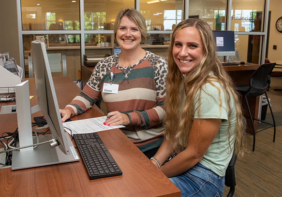 Student with instructor on computer in registration area